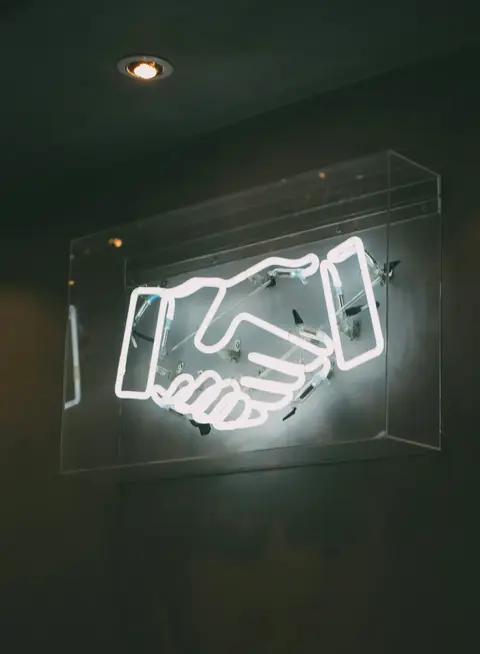a neon sign with handshake on it