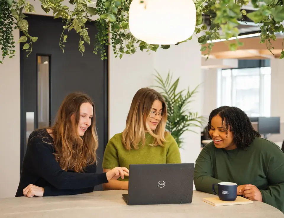 IDHL employees sitting around a laptop, smiling