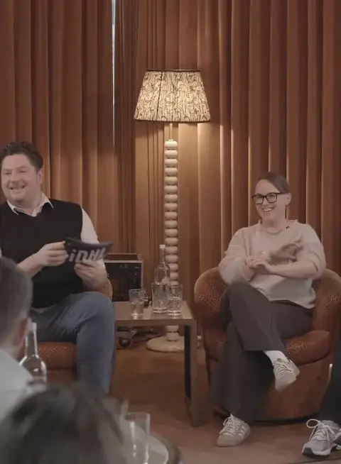 3 people sat in front of crowd, engaged in a fireside chat