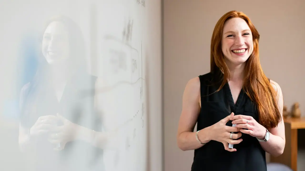 a woman standing next to a white board